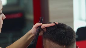 Frauenfriseur, der dem jungen Mann Haarschnitt macht Sie unter Verwendung der Scheren und des Kammes stock video Frauenfriseur, der dem jungen Mann Haarschnitt macht Sie unter Verwendung der Scheren und des Kammes stock video