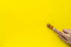 Frauenhand mit kleinem gelbem Spielzeugauto auf einem gelben Hintergrund Freier Platz für Text lizenzfreie stockfotos Frauenhand mit kleinem gelbem Spielzeugauto auf einem gelben Hintergrund Freier Platz für Text lizenzfreie stockfotos
