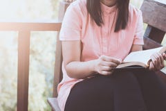 Frauenhandholding und -lesung ein Buch auf dem Stuhl am Haus lizenzfreies stockbild Frauenhandholding und -lesung ein Buch auf dem Stuhl am Haus lizenzfreies stockbild