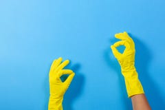 Frauenhände mit den gelben Gummihandschuhen, die ein Gestenbedeutungs-O.K., Draufsicht über blauen Hintergrund machen stockfotografie Frauenhände mit den gelben Gummihandschuhen, die ein Gestenbedeutungs-O.K., Draufsicht über blauen Hintergrund machen stockfotografie