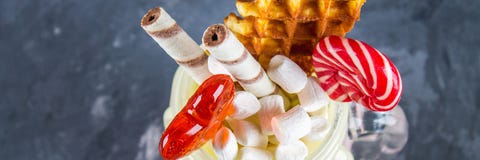 Freakshake od różowego smoothie, śmietanka Monstershake z lizakami, goframi i marshmallow, Krańcowy milkshake w kamieniarza słoju fotografia stock Freakshake od różowego smoothie, śmietanka Monstershake z lizakami, goframi i marshmallow, Krańcowy milkshake w kamieniarza słoju fotografia stock