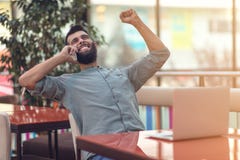 Freelancer farpado feliz entusiasmado que lê o e-mail com resultados sobre a vitória na competição em linha moderna que senta-se foto de stock Freelancer farpado feliz entusiasmado que lê o e-mail com resultados sobre a vitória na competição em linha moderna que senta-se foto de stock