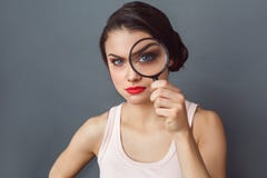freestyle Vrouw status geïsoleerd op grijs met vergrootglas die camera verdacht close-up kijken royalty-vrije stock afbeeldingen freestyle Vrouw status geïsoleerd op grijs met vergrootglas die camera verdacht close-up kijken royalty-vrije stock afbeeldingen