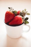 Fresas en una taza blanca del esmalte imágenes de archivo libres de regalías Fresas en una taza blanca del esmalte imágenes de archivo libres de regalías
