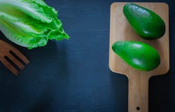 Fresh avocado on a cutting board with lettuce leaves on a wooden background. Healthy food.copy space royalty free stock photography Fresh avocado on a cutting board with lettuce leaves on a wooden background. Healthy food.copy space royalty free stock photography