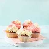 Fresh cupcakes with whipped cream and cream are served on a plate on a soft blue background close-up. Copy space. royalty free stock image Fresh cupcakes with whipped cream and cream are served on a plate on a soft blue background close-up. Copy space. royalty free stock image