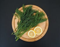 Fresh green dill on a wooden cutting board with lemon on the black background stock images Fresh green dill on a wooden cutting board with lemon on the black background stock images