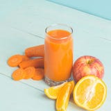 Fresh juice from carrots and orange apples in a glass on a wooden blue background. Selective focus. Copy space royalty free stock images Fresh juice from carrots and orange apples in a glass on a wooden blue background. Selective focus. Copy space royalty free stock images