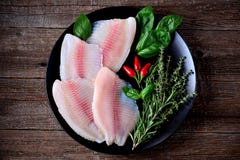 Fresh Raw Fillet Of Tilapia Fish With Thyme, Rosemary, Basil And Chili Pepper. Royalty Free Stock Image Fresh Raw Fillet Of Tilapia Fish With Thyme, Rosemary, Basil And Chili Pepper. Royalty Free Stock Image