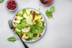 Fresh salad with pineapple, spinach, avocado and pomegranate on gray kitchen table, top view. Healthy vegan eating, clean food,
