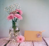 Fresh white and pink flowers, heart next to vintage empty card over wooden table. vintage filtered and toned image royalty free stock image Fresh white and pink flowers, heart next to vintage empty card over wooden table. vintage filtered and toned image royalty free stock image