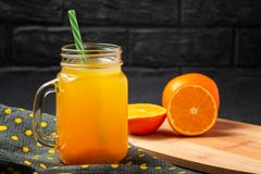 Freshly made citrus juice from oranges in a jar-mug with a straw on grey table stock photo Freshly made citrus juice from oranges in a jar-mug with a straw on grey table stock photo