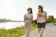 Freundinnen gehen in den Park in der Natur Mädchen gehen entlang den grünen Rasen, sprechen, haben Spaß lizenzfreies stockfoto Freundinnen gehen in den Park in der Natur Mädchen gehen entlang den grünen Rasen, sprechen, haben Spaß lizenzfreies stockfoto