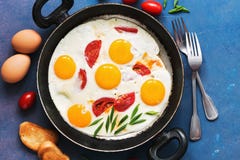 Fried Eggs With Tomatoes Served In A Pan With Toast On A Blue Background. Flat Lay, Tinted Photo. Stock Images