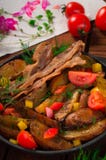 Fried potatoes with bacon and fresh tomatoes in the frying pan. Wooden rustic background. Top view stock photography Fried potatoes with bacon and fresh tomatoes in the frying pan. Wooden rustic background. Top view stock photography