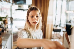 A friendly young slim girl with blonde long hair,wearing casual style,passes a coffee in a cozy coffee shop. stock images A friendly young slim girl with blonde long hair,wearing casual style,passes a coffee in a cozy coffee shop. stock images