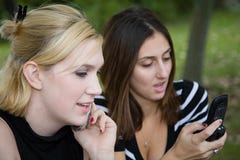 Friends On Cell Phone Together (Beautiful Young Blonde And Brunette Girls) Royalty Free Stock Image