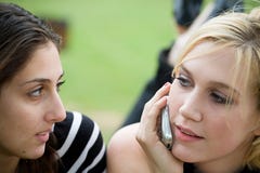 Friends On Cell Phone Together (Beautiful Young Blonde And Brunette Girls) Royalty Free Stock Photos