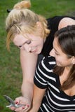 Friends On Cell Phone Together (Beautiful Young Blonde And Brunette Girls) Royalty Free Stock Photos