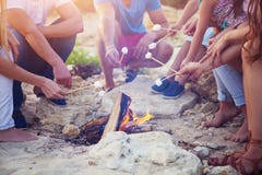 Friends sitting on the sand at the beach in circle with marshmallow royalty free stock photo Friends sitting on the sand at the beach in circle with marshmallow royalty free stock photo