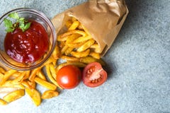 Frieten, gebraden aardappels met ketchup en tomaten op de achtergrond van grijs-blauw graniet stock fotografie Frieten, gebraden aardappels met ketchup en tomaten op de achtergrond van grijs-blauw graniet stock fotografie