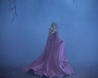 A frightened girl blonde runs in a thick fog. On the elf, a luxurious pink dress with a long train and a raincoat. The Royalty Free Stock Photography A frightened girl blonde runs in a thick fog. On the elf, a luxurious pink dress with a long train and a raincoat. The Royalty Free Stock Photography