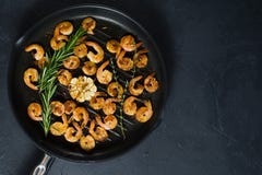 Frigideira com os camar?es do rei e os ramos fritados dos alecrins e do tomilho foto de stock Frigideira com os camar?es do rei e os ramos fritados dos alecrins e do tomilho foto de stock