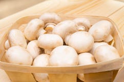 Frische Pilzchampignons in einem Korb auf einem hölzernen Hintergrund lizenzfreie stockfotografie Frische Pilzchampignons in einem Korb auf einem hölzernen Hintergrund lizenzfreie stockfotografie