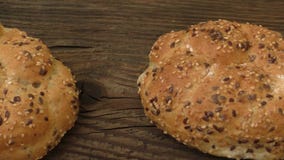 Frische Roggenbrötchen mit Samen des indischen Sesams auf einem hölzernen Hintergrund stock footage Frische Roggenbrötchen mit Samen des indischen Sesams auf einem hölzernen Hintergrund stock footage
