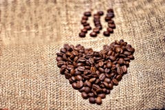 Frische und aromatische Kaffeebohnen auf Weinlesestoff lizenzfreies stockbild Frische und aromatische Kaffeebohnen auf Weinlesestoff lizenzfreies stockbild