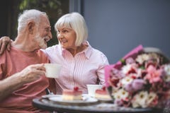 Froher älterer Mann und Frau, die bei Tisch im Café sitzt lizenzfreies stockfoto Froher älterer Mann und Frau, die bei Tisch im Café sitzt lizenzfreies stockfoto