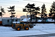 Front-end loader with wheels on a construction site in winter against the backdrop of sunset and spruce trees. stock photos Front-end loader with wheels on a construction site in winter against the backdrop of sunset and spruce trees. stock photos