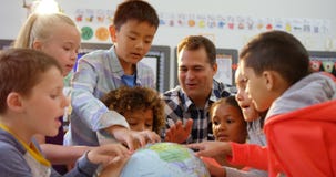 Front view of Caucasian male teacher teaching the kids about the globe in the classroom 4k stock video footage Front view of Caucasian male teacher teaching the kids about the globe in the classroom 4k stock video footage