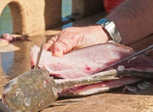 Hands of a fisherman filleting a fish at a marina cleaning station