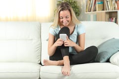 Happy teenage girl using smart phone on a couch stock image Happy teenage girl using smart phone on a couch stock image