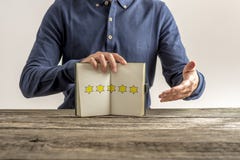 Front view of a man presenting an open notepad with five golden stock photo Front view of a man presenting an open notepad with five golden stock photo