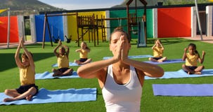 Frontowy widok żeńskiego nauczyciela nauczania schoolkids wykonywać joga w szkolnym boisku 4k zbiory wideo Frontowy widok żeńskiego nauczyciela nauczania schoolkids wykonywać joga w szkolnym boisku 4k zbiory wideo