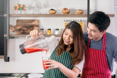 Frullato di versamento della fragola della donna graziosa in un vetro immagine stock Frullato di versamento della fragola della donna graziosa in un vetro immagine stock