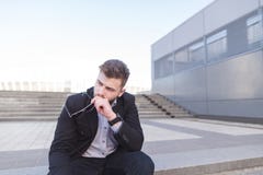 Frustrated businessman is sitting on the ladder at the sad. A depressed man is sitting on the street royalty free stock photography Frustrated businessman is sitting on the ladder at the sad. A depressed man is sitting on the street royalty free stock photography