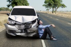 Frustrierter Geschäftsmann, der nahe einem defekten Auto sitzt stockfotos Frustrierter Geschäftsmann, der nahe einem defekten Auto sitzt stockfotos