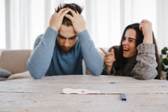 Frustrierter Mann und glückliche Frau mit positivem Test lizenzfreies stockfoto Frustrierter Mann und glückliche Frau mit positivem Test lizenzfreies stockfoto