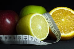 Frutta fresca: mele, arancia affettata e limone con nastro adesivo di misurazione Priorità bassa nera immagine stock libera da diritti Frutta fresca: mele, arancia affettata e limone con nastro adesivo di misurazione Priorità bassa nera immagine stock libera da diritti