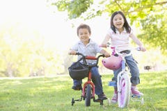Frère et soeur à l'extérieur sur le sourire de bicyclettes image stock Frère et soeur à l'extérieur sur le sourire de bicyclettes image stock