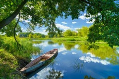 Frühlingssommerlandschaftsblauer Himmel bewölkt Flussboots-Grünbäume Frühlingssommerlandschaftsblauer Himmel bewölkt Flussboots-Grünbäume