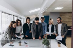 Full concentration at work. Group of young business people working and communicating while standing in modern office stock image Full concentration at work. Group of young business people working and communicating while standing in modern office stock image