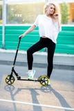 Full-length photo of curly-haired athletic woman kicking on scooter in park stock photos Full-length photo of curly-haired athletic woman kicking on scooter in park stock photos