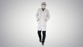 Walking young male doctor wearing surgical mask on gradient background. stock image Walking young male doctor wearing surgical mask on gradient background. stock image