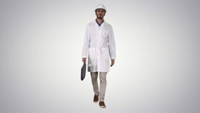 Professional engineer with suitcase and in helmet walking on gradient background. stock footage Professional engineer with suitcase and in helmet walking on gradient background. stock footage