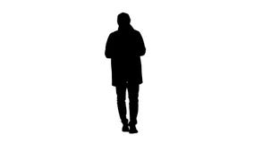 Silhouette Handsome man in cloak walking and texting message on the phone. stock image Silhouette Handsome man in cloak walking and texting message on the phone. stock image