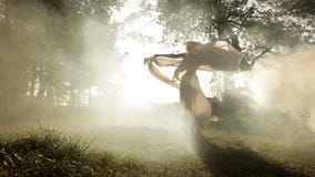 Full-length view of the charming woman dancing and swaying round with the shawl in the fog. Forest location.